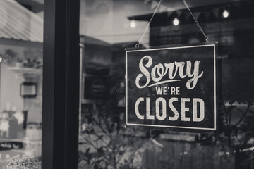 " Sorry we're closed " sign in black and white, on shop glass door.monotone.