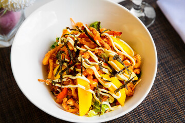 Delicious salad with seafood fried in breadcrumbs, vegetables and fruits served in a white plate close up. Healthy food.