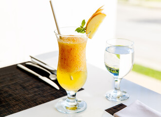 A glass of healthy Apple juice drink with pulp decorated with a slice of Apple and glass of water served on the table. Healthy diet food.