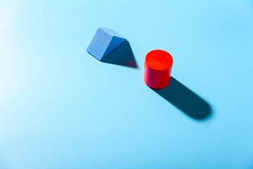 Blue background with red geometric figures casting shadows in a simple composition.