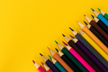 Colored pencils on yellow background with copy space.  Pencils on the corner. Back to school. Educational solution.