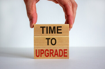 Male hand placing a block with word 'time' on top of a blocks tower with words 'to upgrade'. White table. Beautiful white background. Copy space. Business concept.