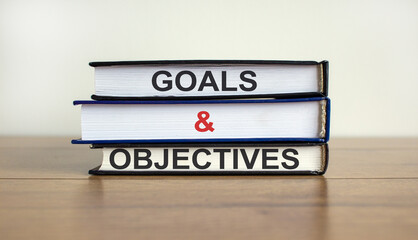Books with text 'goals and objectives' on beautiful wooden table. White background. Business concept. Copy space.