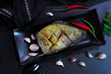Thai crispy gourami fish or Sepat Siam fish or Pla salid in Thai language displayed on the black dish