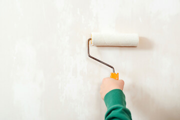 Obraz premium Worker paint wall by the rollers brush. Banner, copy space for text. Hand holding rollerb brush. Boy painting wall in room.