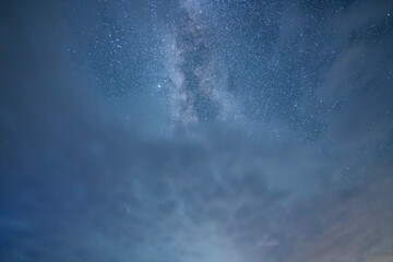Beautiful starry sky with bright milky way galaxy and long exposure clouds. Night landscape. Astronomical background.