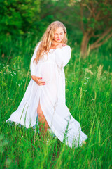 Beautiful young pregnant woman relaxing in nature on a beautiful sunny day.