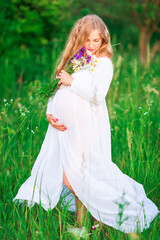 Beautiful young pregnant woman relaxing in nature on a beautiful sunny day.