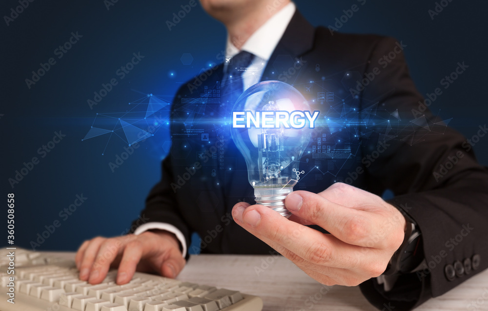 Wall mural businessman holding light bulb with energy inscription, innovative technology concept