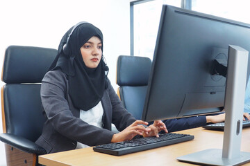 Beautiful Muslim woman call center concentrating at work typing keyboard while solving problems from customers