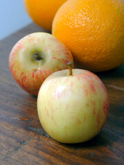 Two Apples and Oranges on a wooden plank. Close up. 