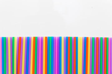 A strip of many plastic colored straws arranged in a row. Isolated