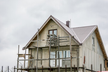 The process of building a private house cottage, scaffolding around the house of stone and concrete