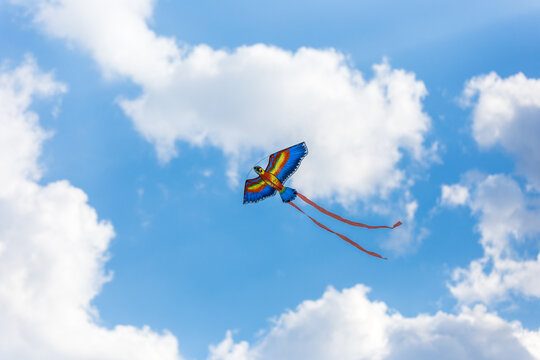 A large multicolored kite on a bright blue sky on a Sunny day. Bright toy for children