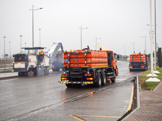 The road miller removes the asphalt from the road and the watering machine washes away the remains. Roadworks are underway.