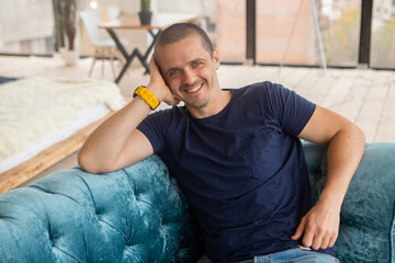 Smiling man looking in camera sitting on sofa