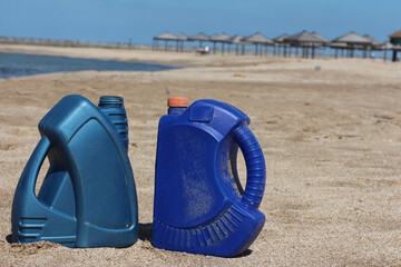 Blue plastic canister of motor oil on the beach.