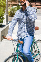 Attractive man calling with his mobile phone on a fixed gear bicycle in the street.