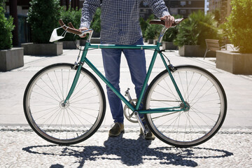 Fototapeta premium Outdoor portrait of handsome young man holding a fixed gear bicycle in the street.