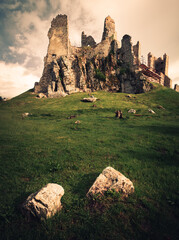 Scenic view of Hrusov Castle in Europe (Slovakia) after the storm on sunny day. Rocks and wood under the hill with castle (ruins) on background. Romantic place - castle on the hill with misty sky.