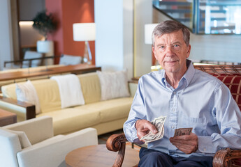 Senior caucasian man holding some US dollar bills as if handing them to the viewer. Composite into...