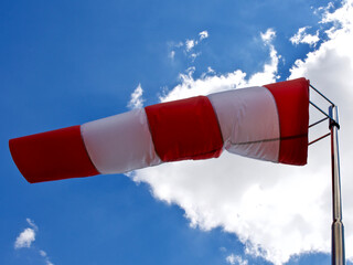 Windsock. Windsock flag. Wind direction indicator. Wind intensity. Windsock in front of blue sky.