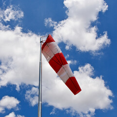 Windsock. Windsock flag. Wind direction indicator. Wind intensity. Windsock in front of blue sky.