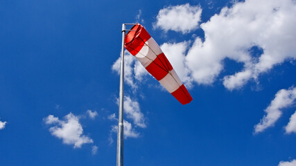 Windsock. Windsock flag. Wind direction indicator. Wind intensity. Windsock in front of blue sky.