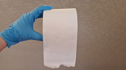 a clean roll of white toilet paper in human hand wearing blue rubber glove