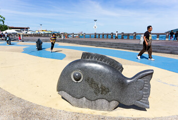 KOTA KINABALU, MALAYSIA - SEPTEMBER 01, 2016: People passing by the dolphin statue at Kota Kinabalu...