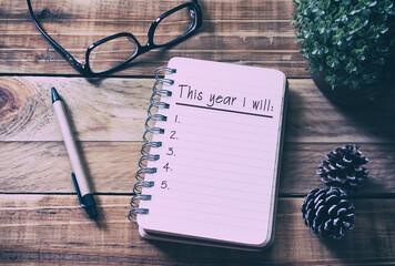 New year goals and resolution concept - This year i will on notepad. Retro style background.
