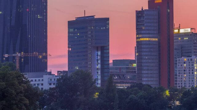 Vienna international center skyscrapers with Kaiserwasser lake reflection view day to night transition timelapse, Donaucity in capital of Austria. Colorful sky with clouds. Boats floating on a water