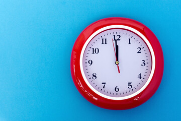 New year concept - Red wall clock pointing at 12 o'clock on blue background