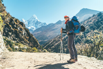 Young hiker backpacker female taking brake in hike walking enjoying valley during high altitude Everest Base Camp route near Dingboche, Nepal. Ama Dablam 6812m on background. Active vacations concept.