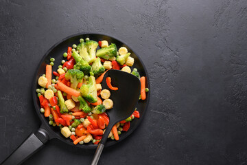 Frozen vegetables in frying pan on black background. View from above.