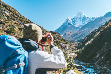 Young hiker backpacker female taking photo mountain view during high altitude Acclimatization walk. Everest Base Camp trekking route, Nepal. Active landscape photographer vacations concept image.