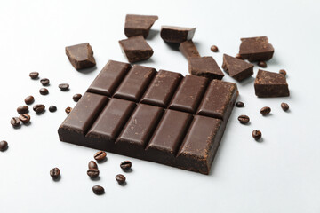 Chocolate bar and coffee seeds on white background