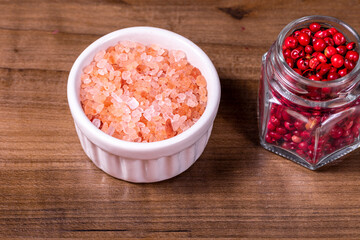 Fototapeta na wymiar Closeup on bowl with pink himalayan salt and glass jar with red peppercorns