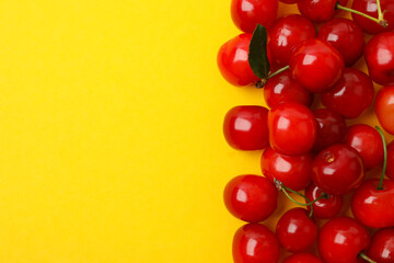 Frame of fresh cherry on yellow background, space for text