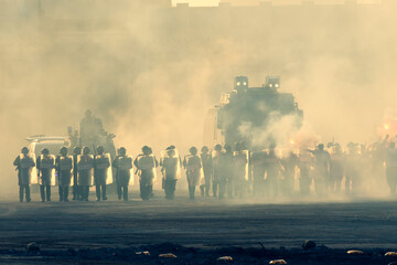 Military police riot response to a protest with tear gas, smoke, fire, explosions. Political expression, riot, protest, demostration and military concept. - obrazy, fototapety, plakaty