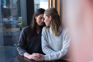 Lesbian couple of women on a date in a cafe. Two gay girlfriends hold hands and flirt in a bistro. Tactile sensations. Lgbt.
