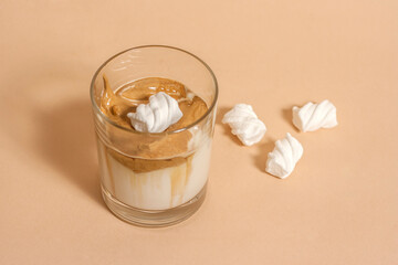 Dalgon coffee in a transparent glass with milk on a pastel background with marshmallows
