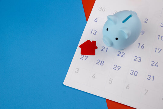 New house purchase, mortgage schedule reminder or real estate payment day, house and piggy bank on white clean calendar.