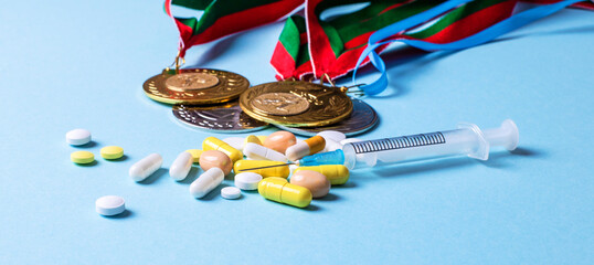 On a blue background, medals, syringe, pills. Doping in sports. Medical and sports concept