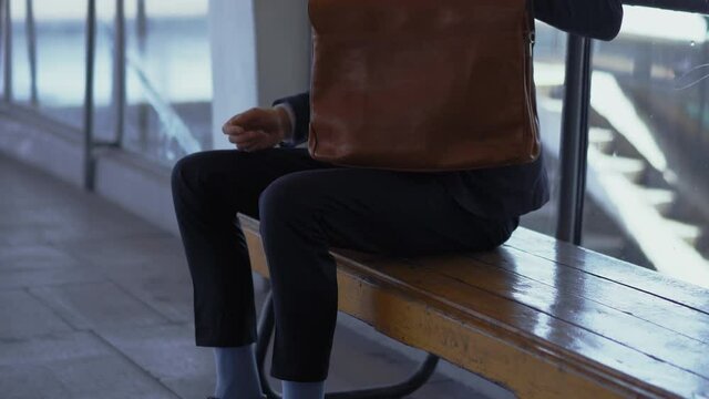 Freelancer man protects briefcase sitting and on bench at metro station, waiting for his train to get to office or clients. Male businessman with a briefcase goes to work. Prores 422.