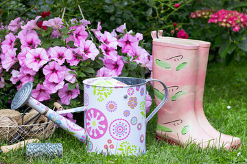 Sommer-Gartendekoration mit Gießkanne, Petunia und pink Gummistiefeln