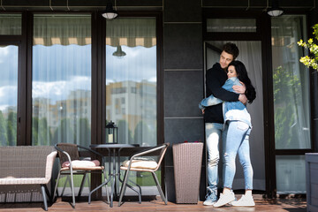 Young couple hugging on terrace near house at daytime