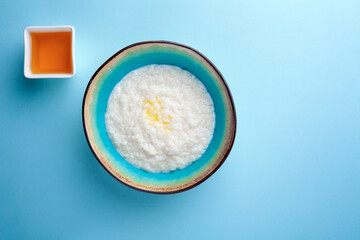 Portion hot of rice porridge in bowl on blue background