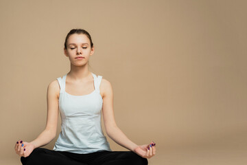 A girl sits in a lotus position and meditates with her eyes closed. Zen practice, breath technique....