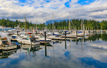 Fototapeta na wymiar Boats docked at Coal Harbor in Vancouver Canada with Stanley Park and Grouse Mountain in the background